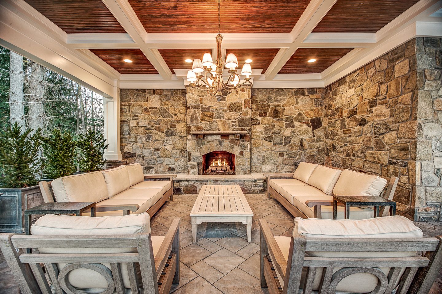 Covered outdoor lounge with coffered ceiling and stone fireplace