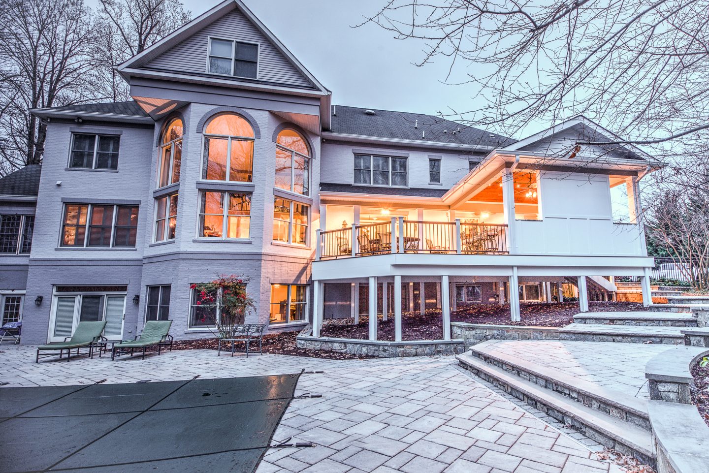 Two-level covered deck and porch with warm lighting at dusk