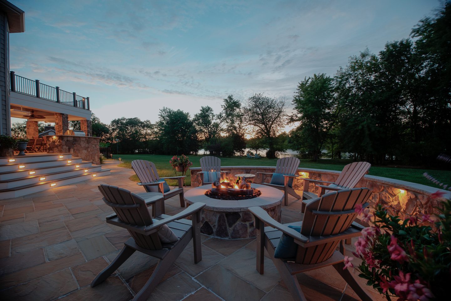 Contemporary fire feature and lounge chairs on a stone terrace at sunset