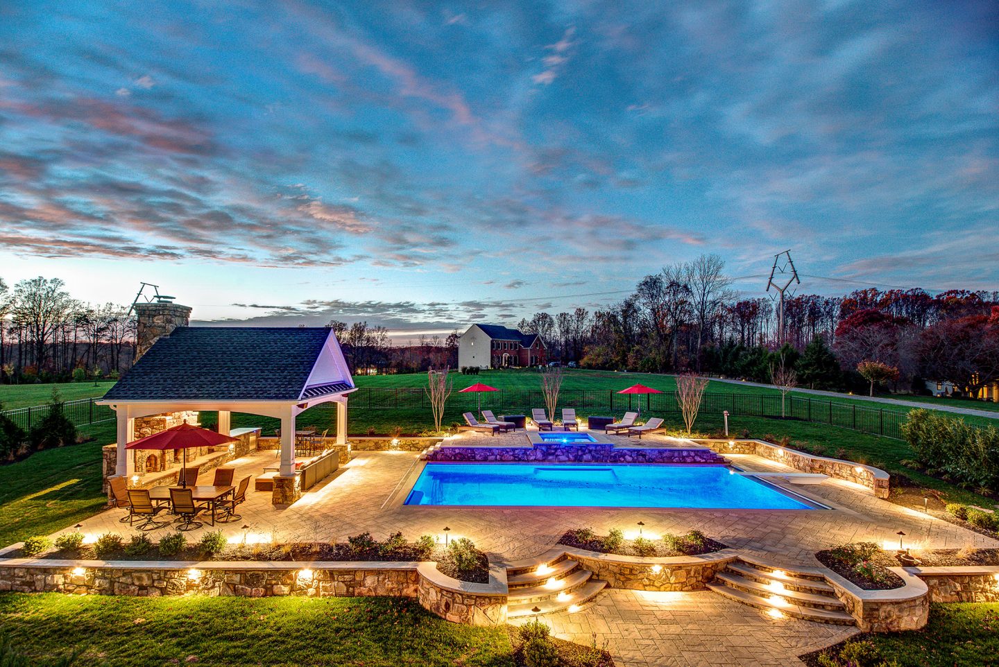 Lit swimming pool and pavilion at dusk