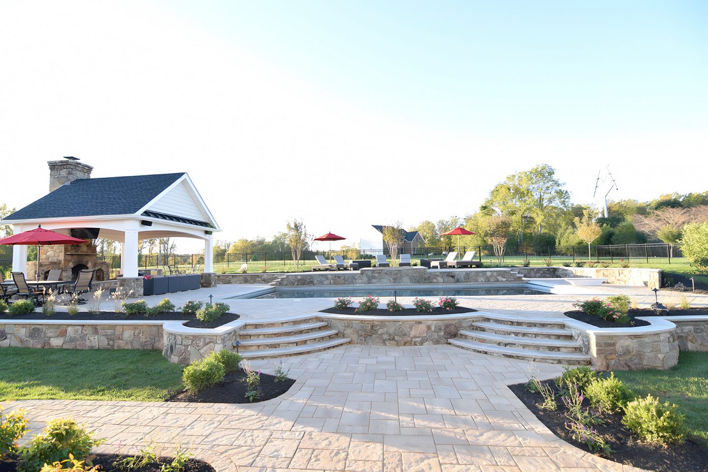 Pavilion with stone chimney in residential backyard pool area