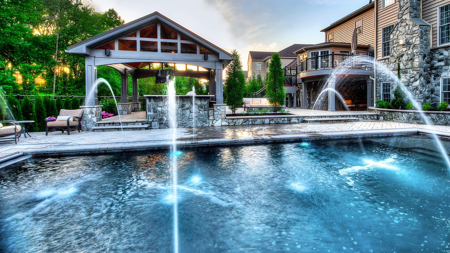 Pool with fountains in a residential backyard at dusk