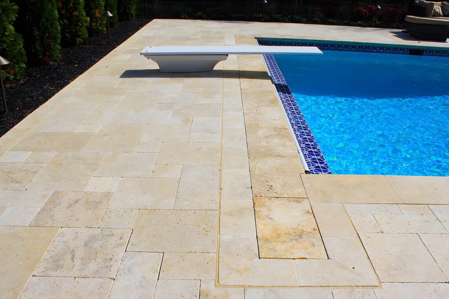 A swimming pool with a stone patio and a diving board