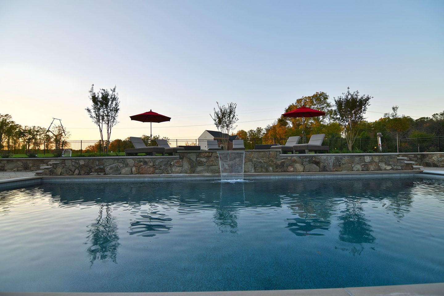 A stone retaining wall with a waterfall feature in a residential pool area