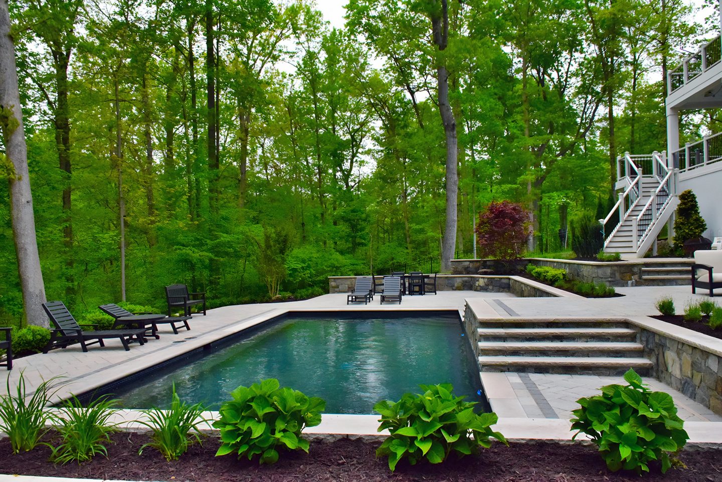 Pool in a residential backyard with stone steps leading into the water