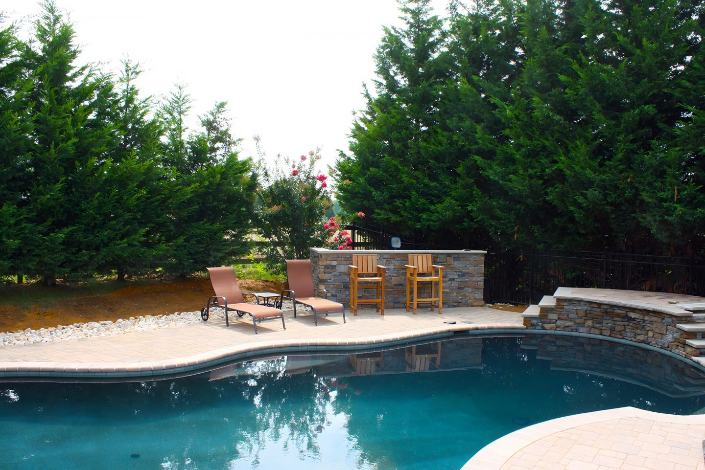Kidney-shaped pool with paved deck in residential backyard